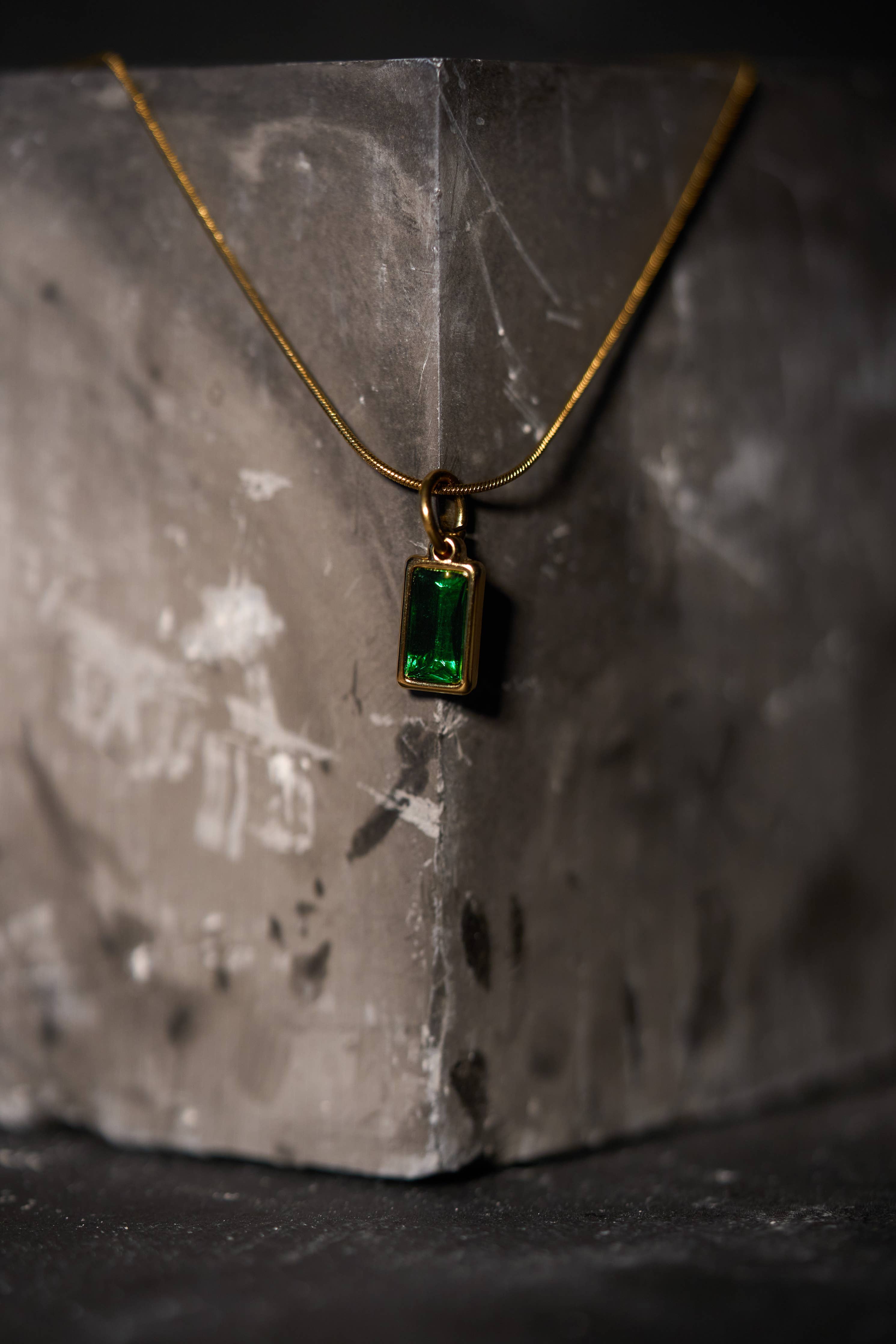 Gold necklace with a rectangular green gemstone pendant
