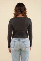 Woman facing away from the camera wearing vintage black, shirred waist, long sleeve top 