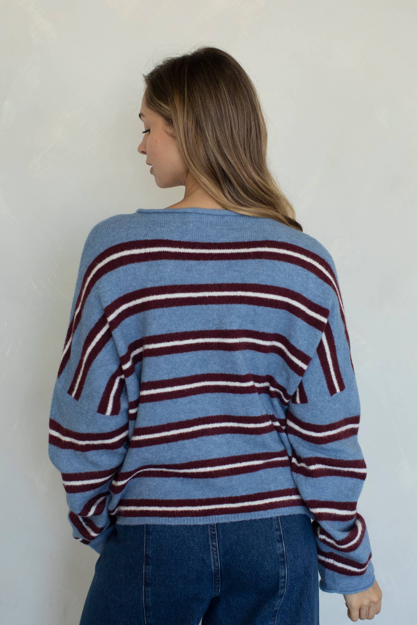 Woman wearing a blue and red striped sweater against a plain background