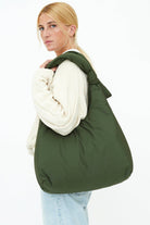 model with big green quilted, puffy, double knot, recycled material shoulder bag