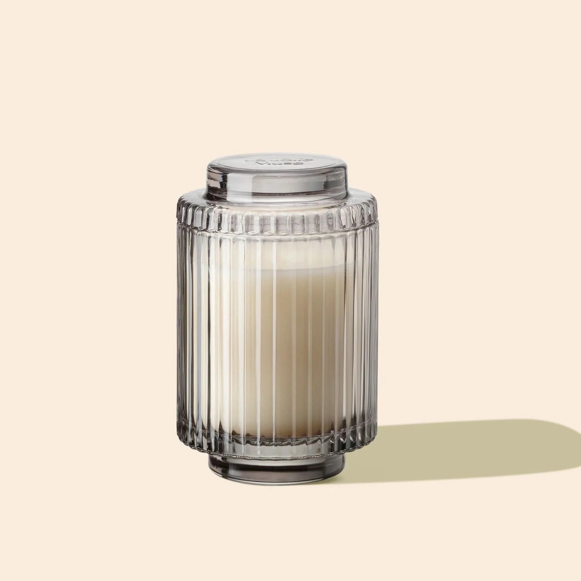 Decorative glass candle holder with a candle on a beige background