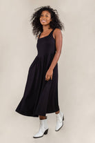 Woman wearing black colored, midi dress, with corset bodice detail and cowboy boots