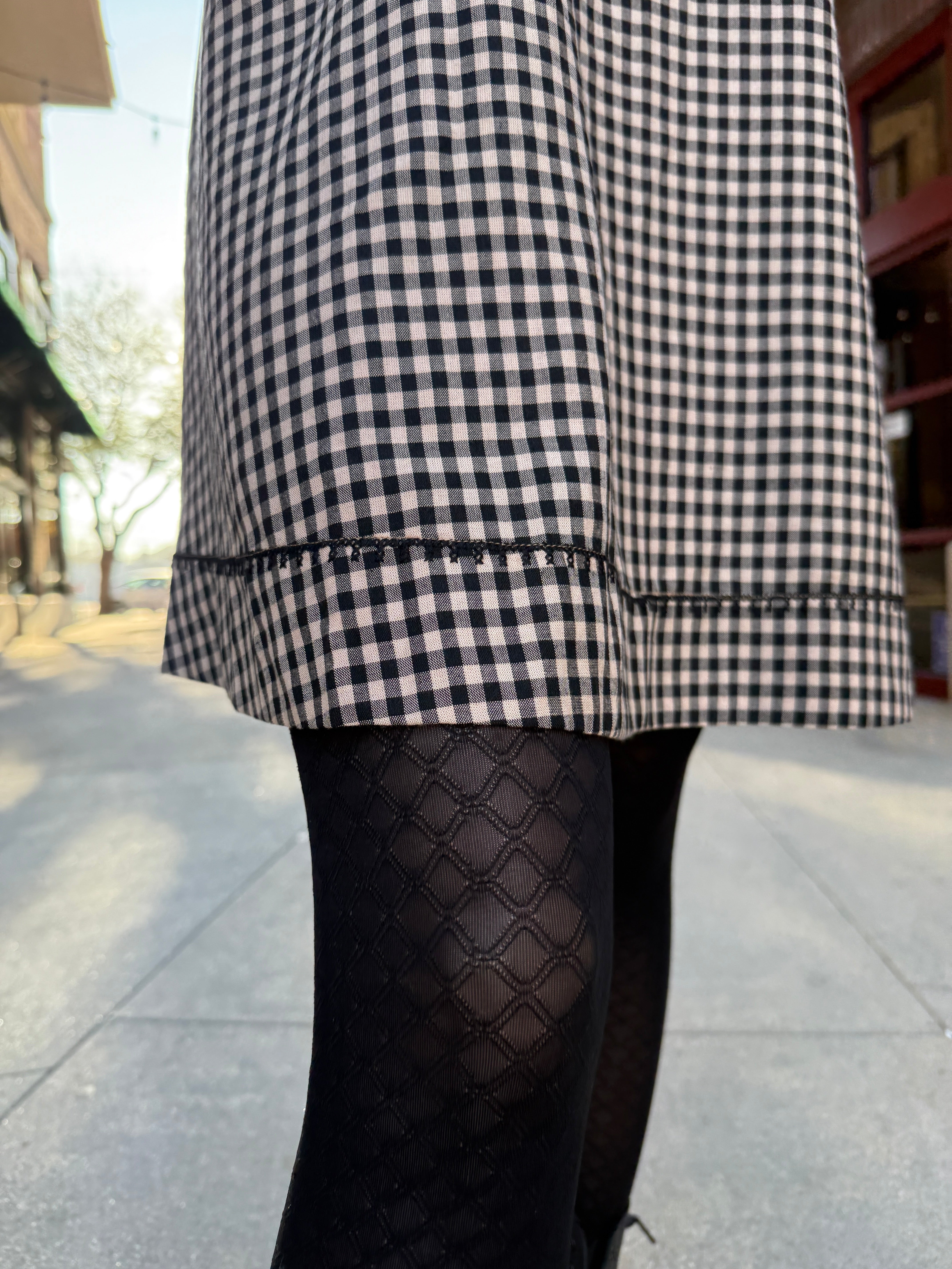 Model wearing Vintage style babydoll dress black and tan gingham pattern with lace details 