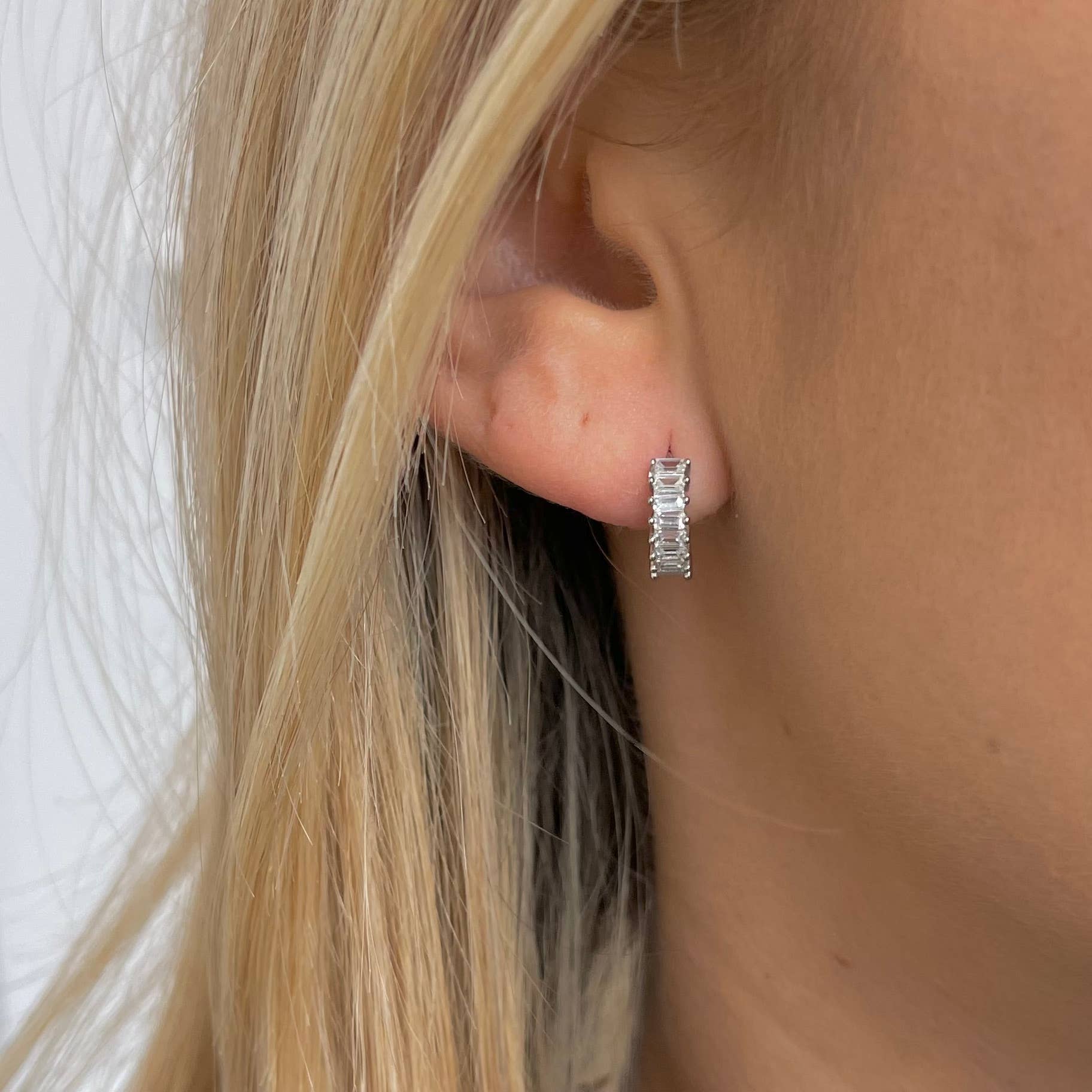 Woman wearing silver diamond huggie earrings 