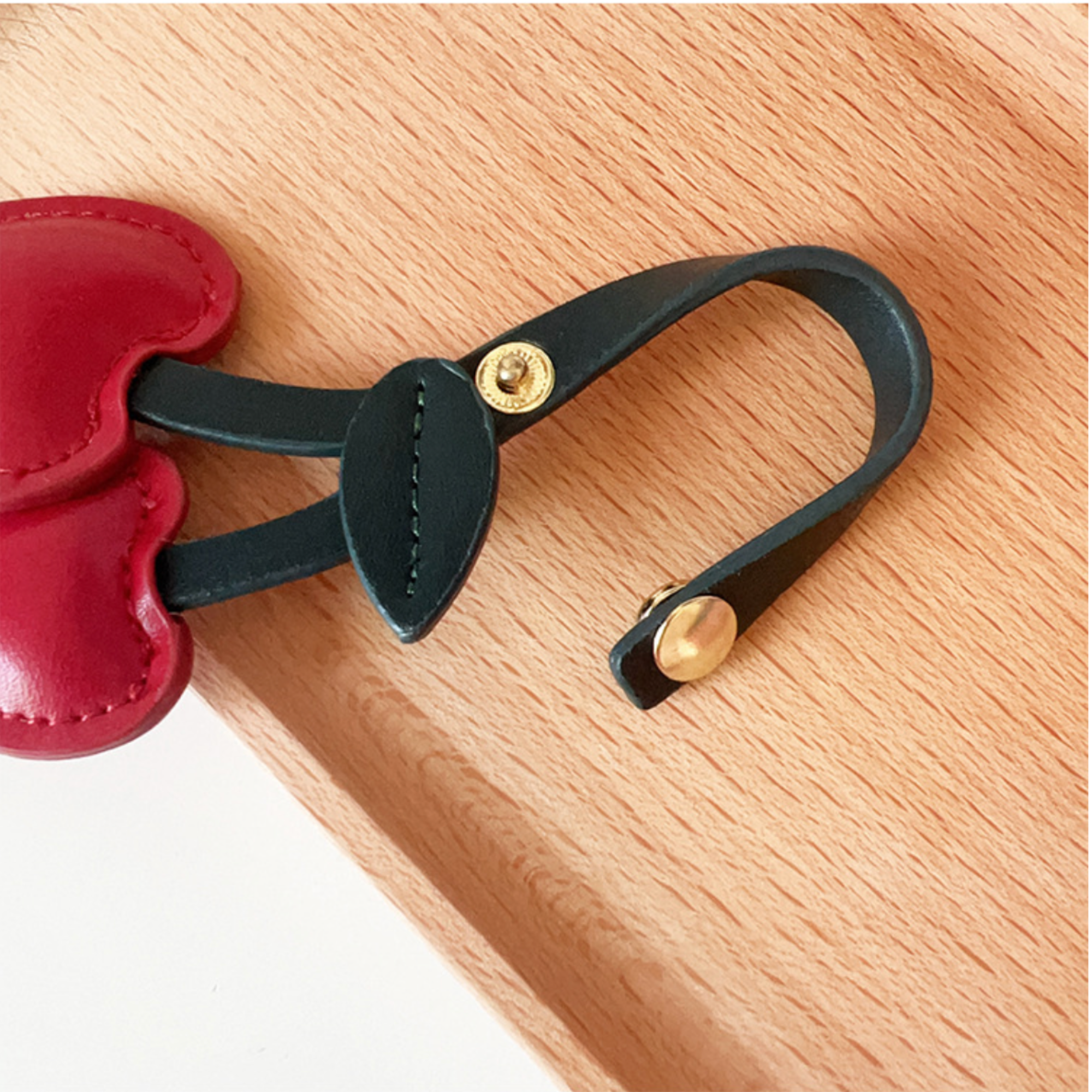 Red Cherry Bag charm on wood background with open button clasp 