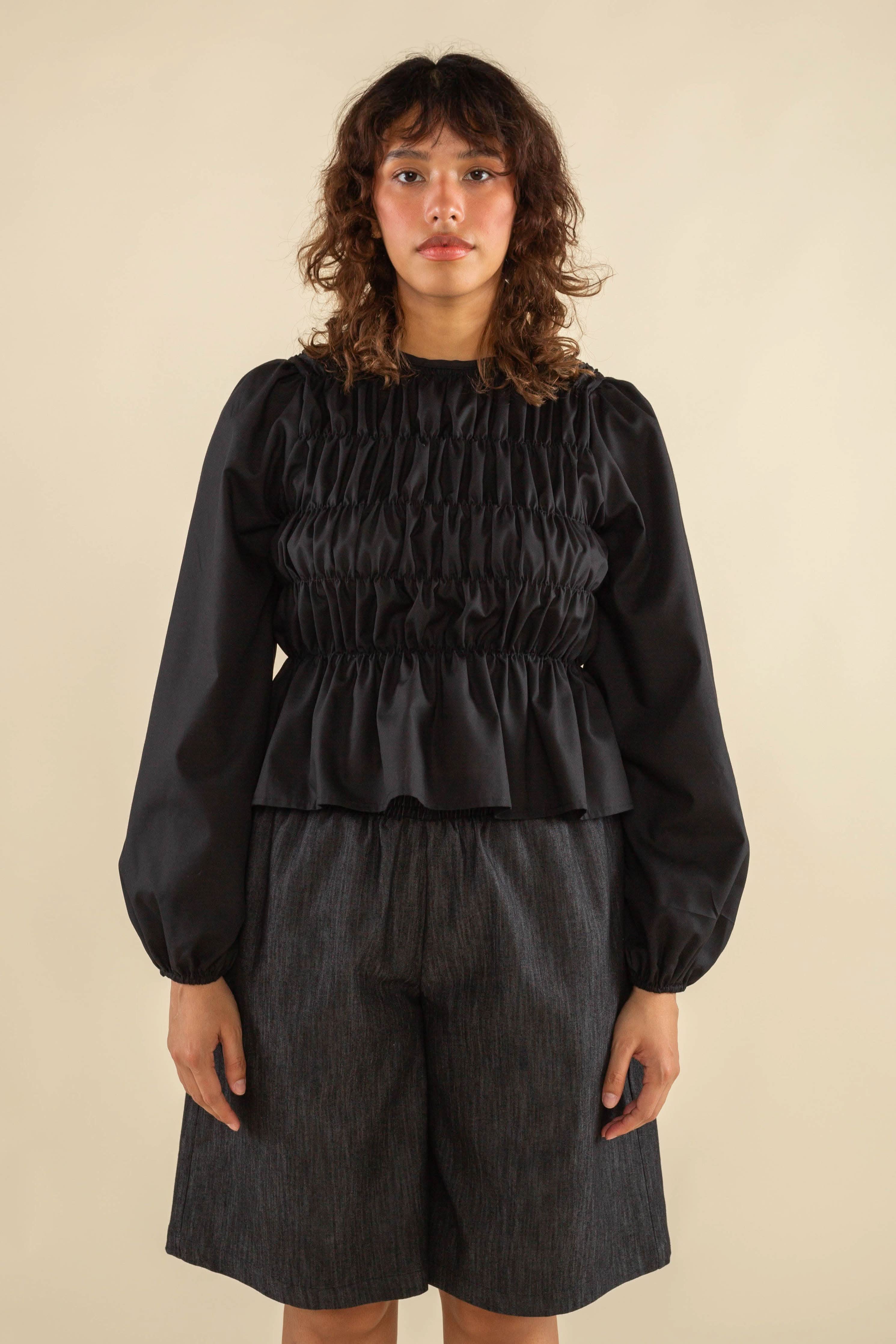 Woman wearing black, bubble long sleeve, shirred, peplum style top