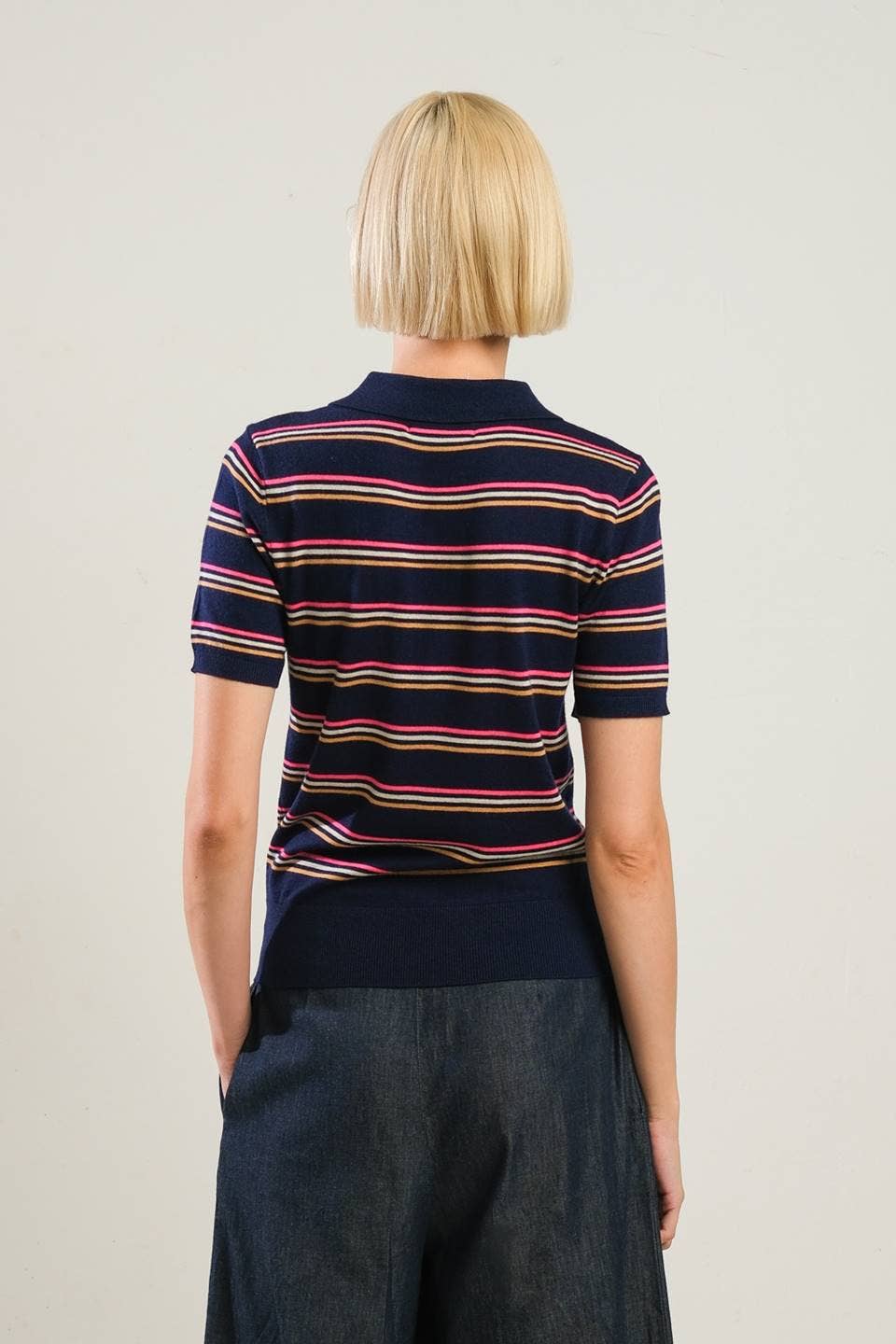 Person wearing a striped polo shirt with a neutral background