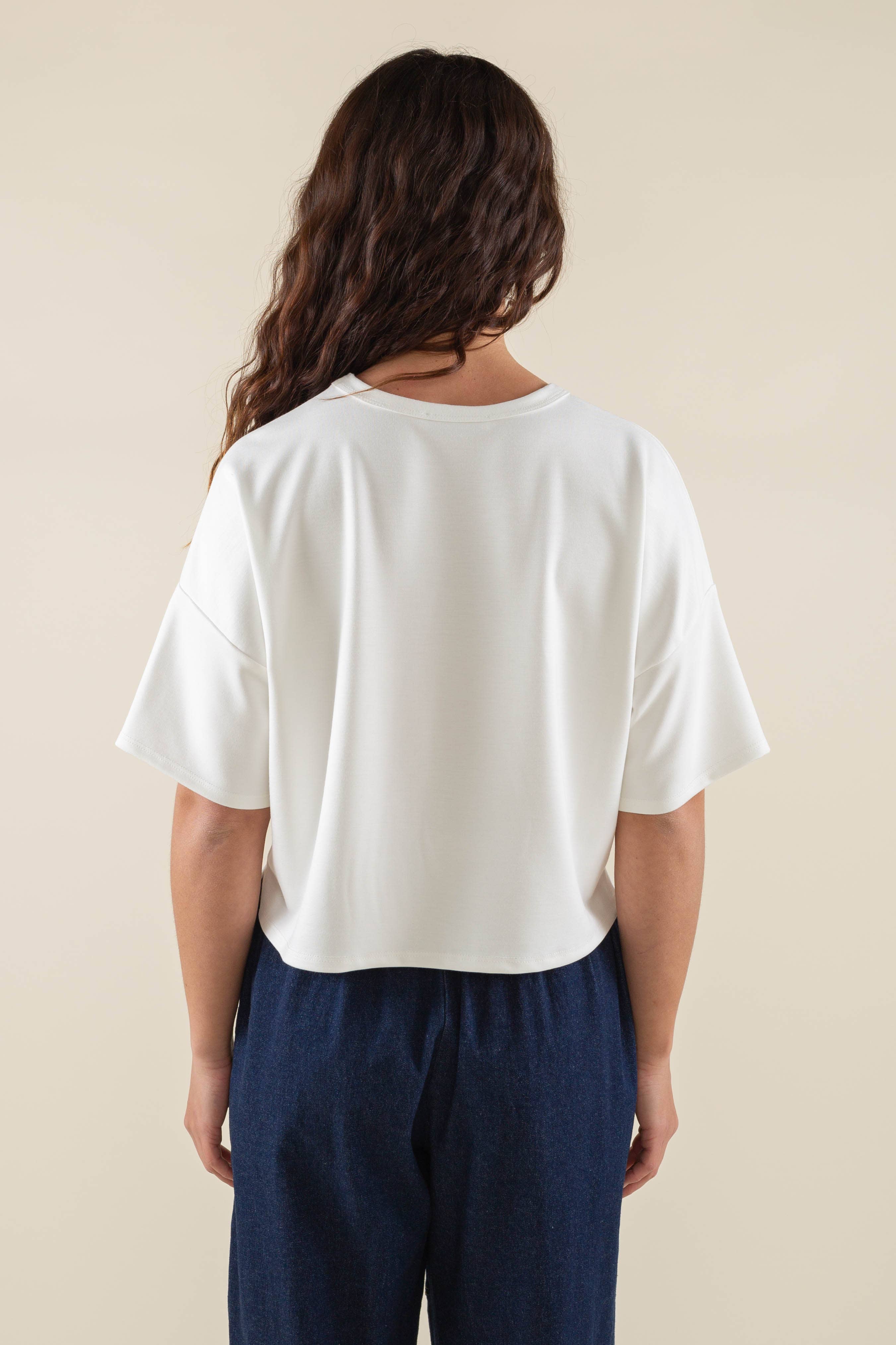 Woman wearing white, short sleeve, jersey, cropped t-shirt and blue jeans 