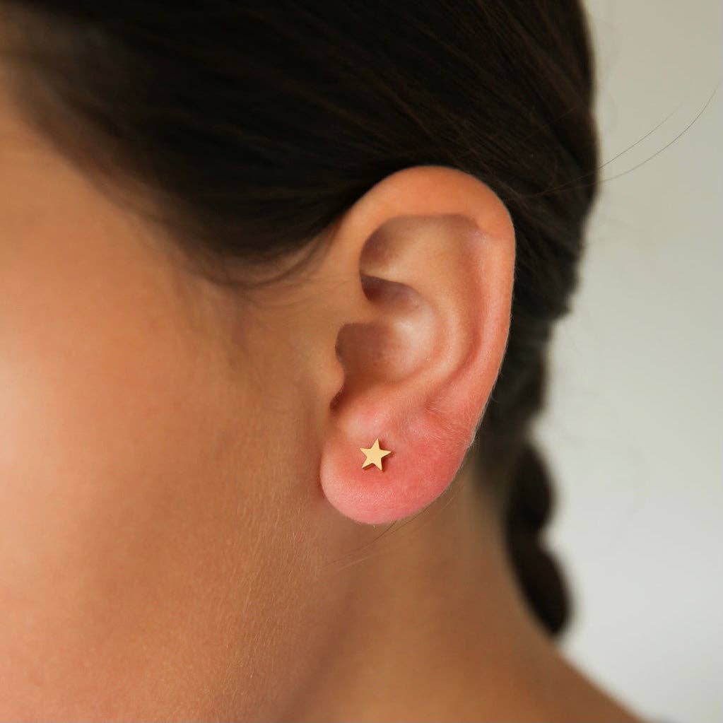 Model wearing flat back thick gold star earrings  