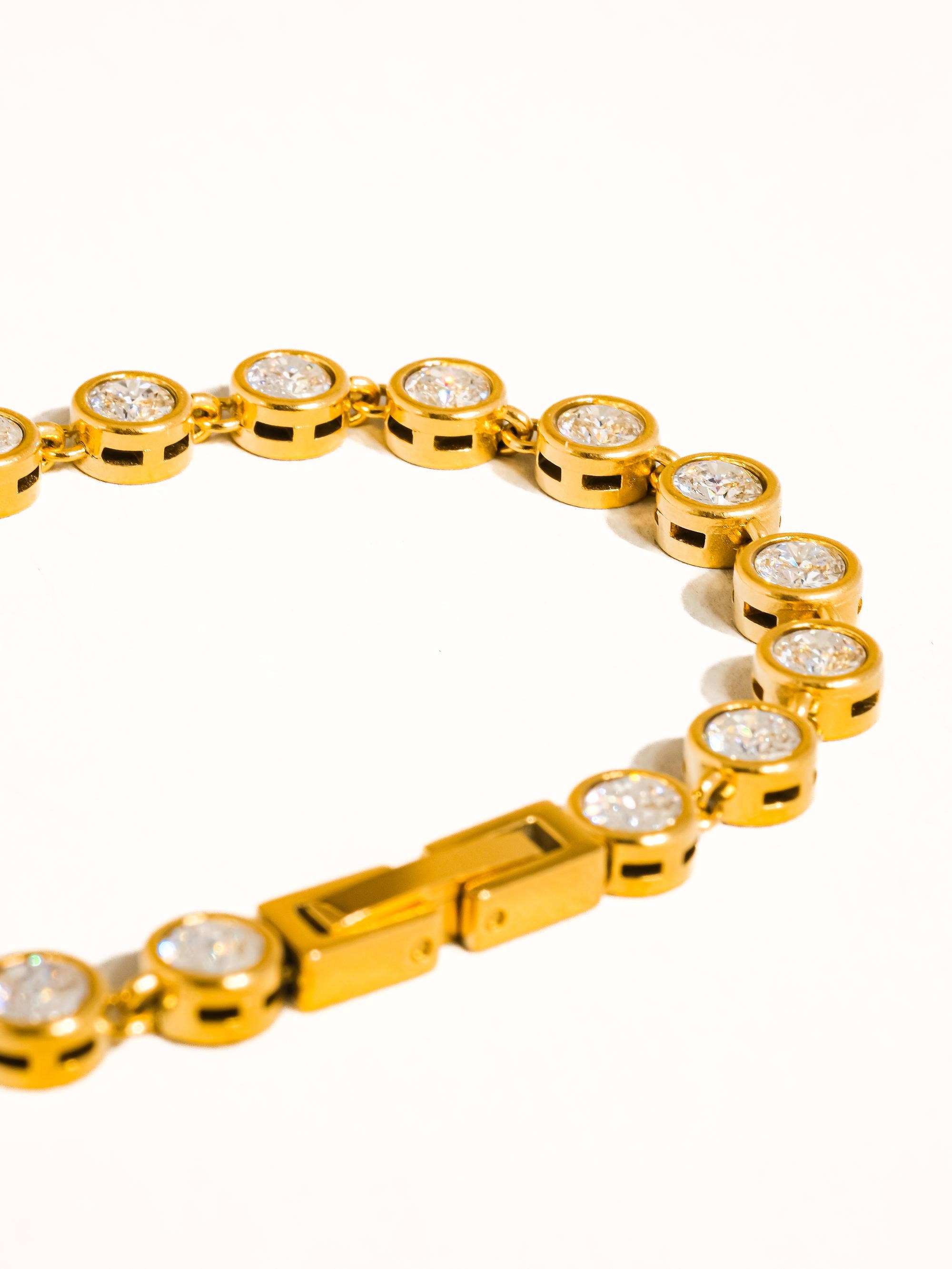 Gold bracelet with diamond-like stones on a white background