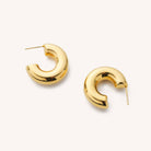 Chunky thick tube hoop earrings laying on a white background 
