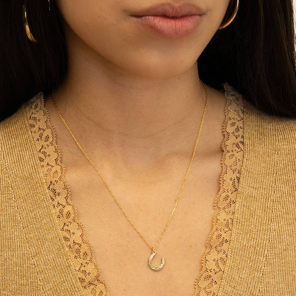 Close-up of a person wearing a gold necklace with a crescent moon pendant.