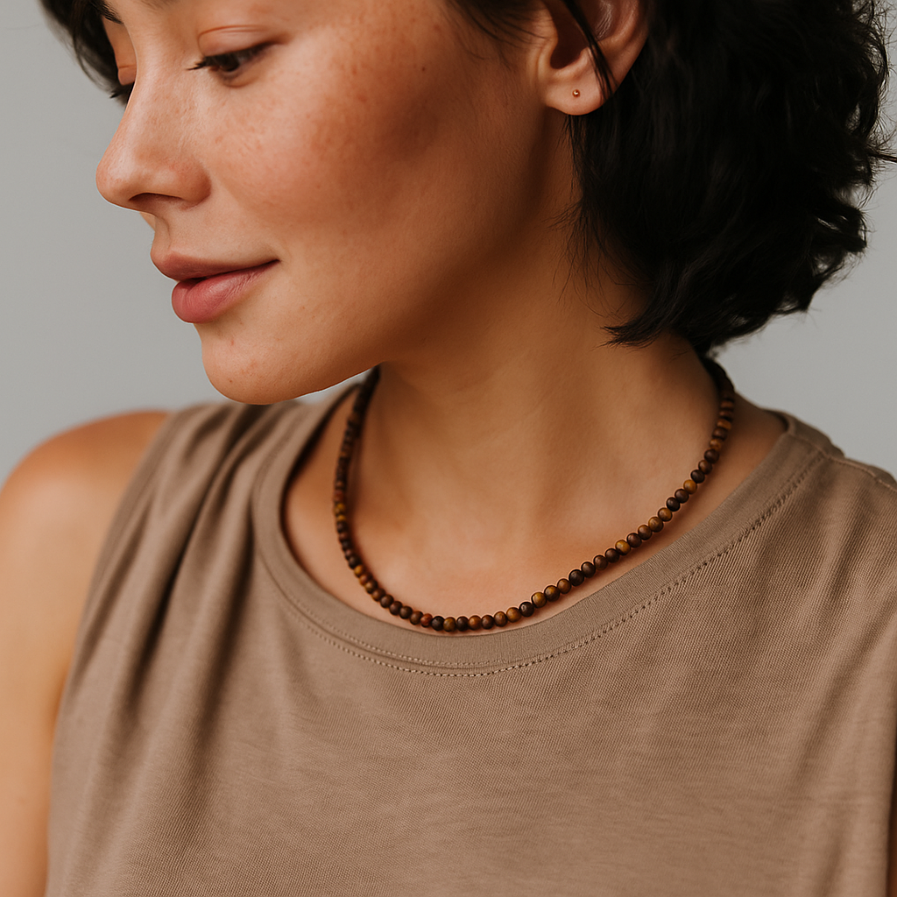 Woman wearing a brown beaded necklace against a neutral background