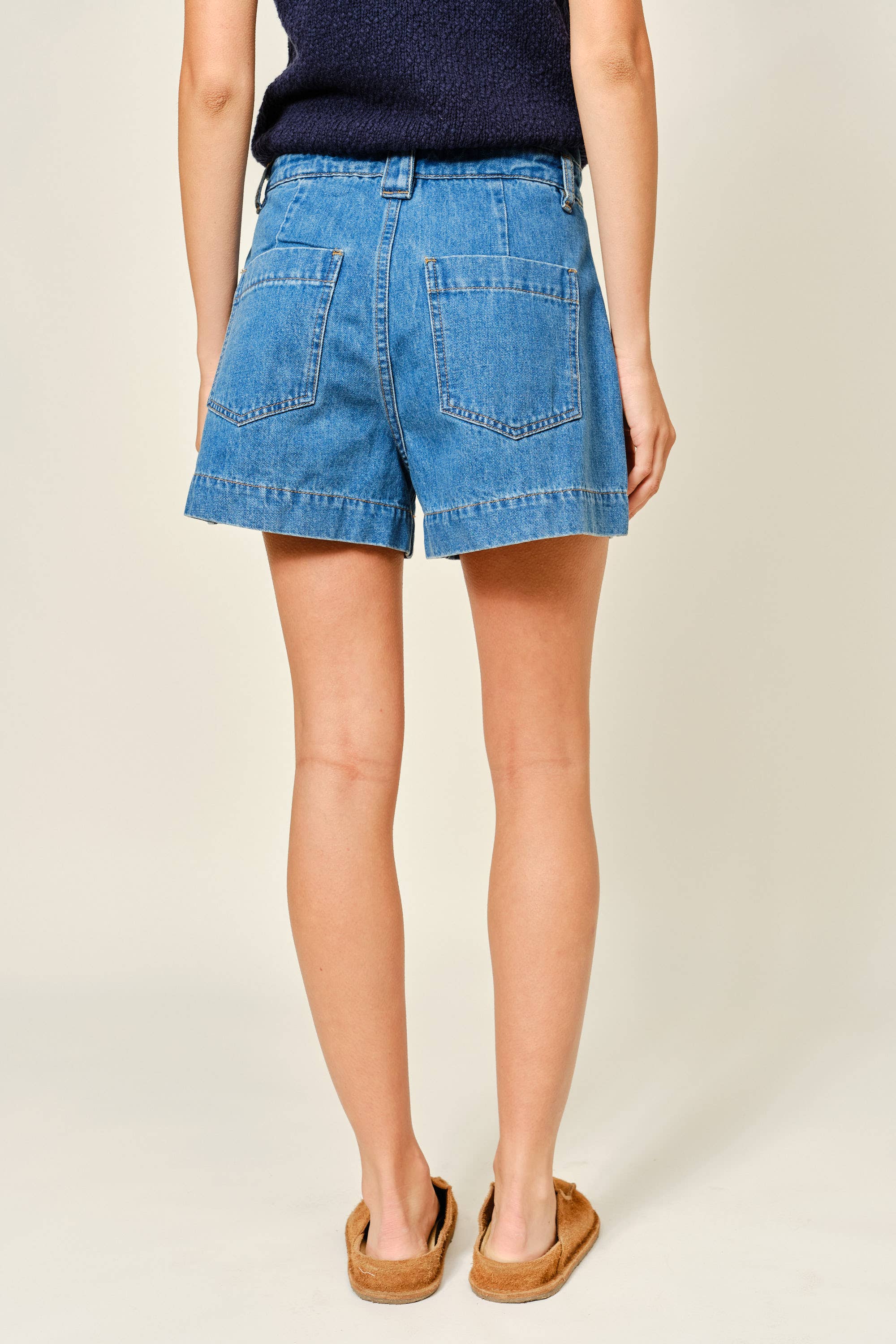 Person wearing blue denim shorts on a plain background