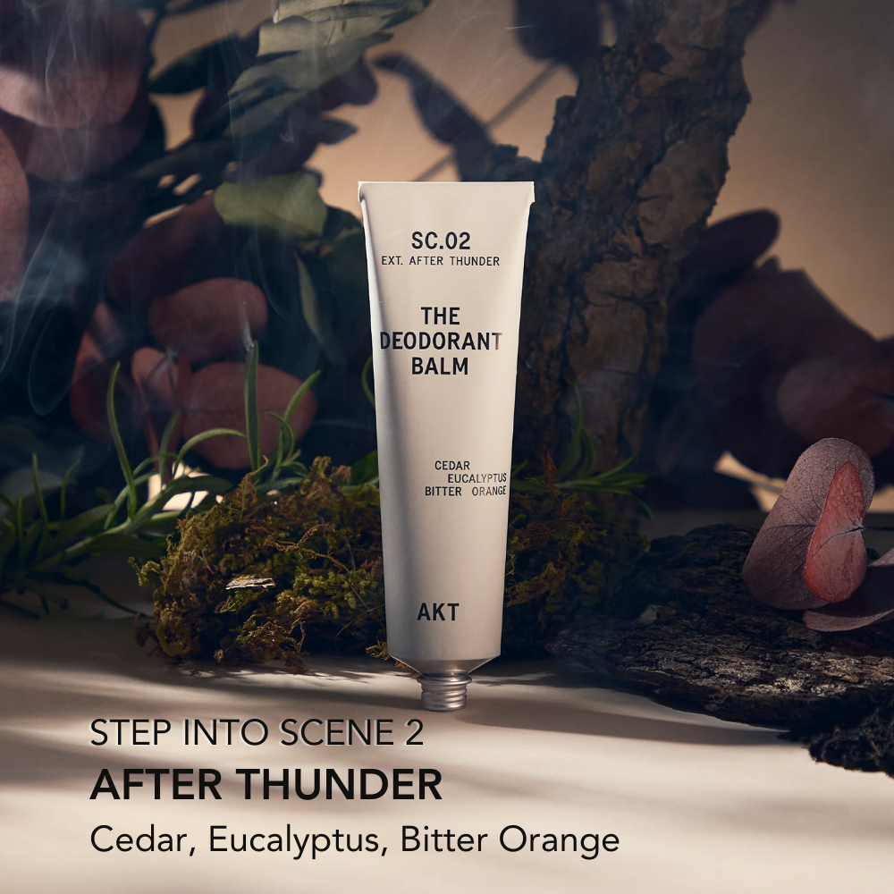 Deodorant balm in gray metal tube standing with greenery in background 