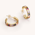 Rainbow colored shimmer hoop earrings laying on a white background 