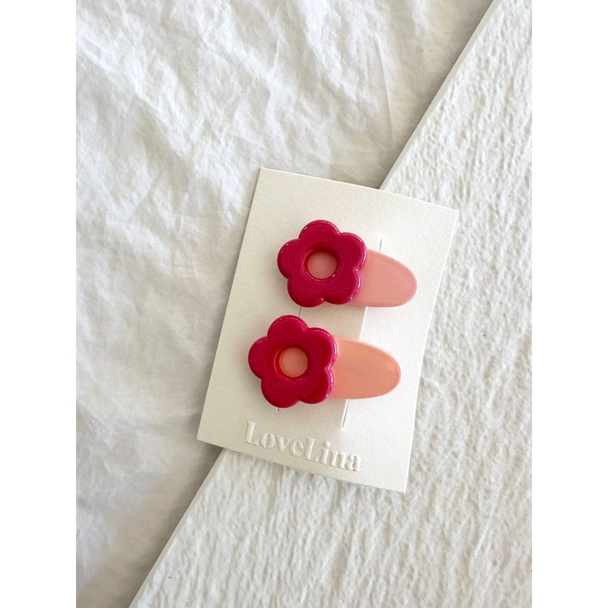 Pair of mini red and pink flower clips, clipped to display card laying on white cloth