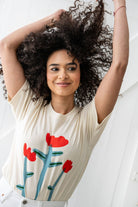 Woman smiling wearing Cream white Tshirt tee with three red tulip doodles on the Tshirt 