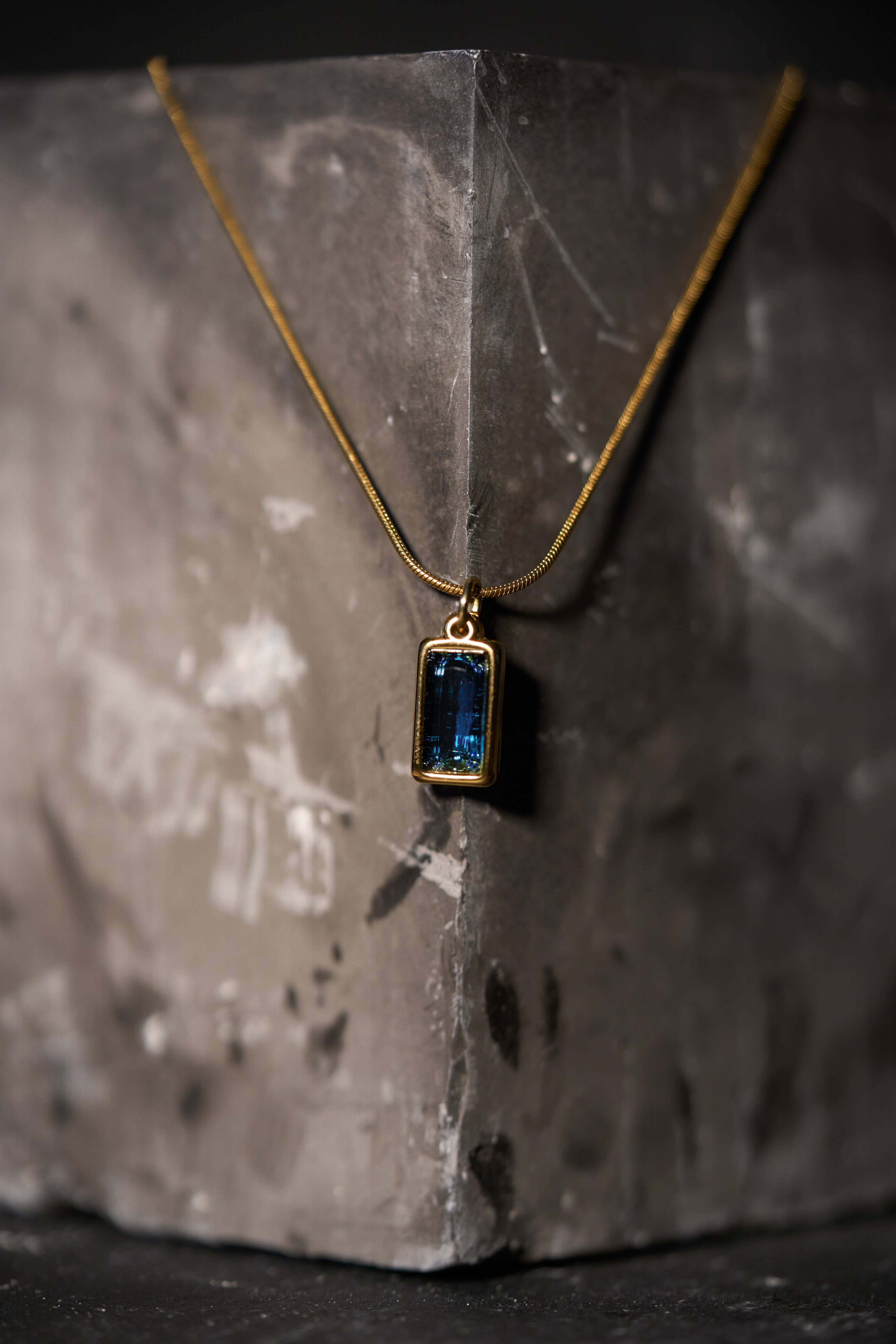 Gold necklace with a rectangular blue gemstone pendant