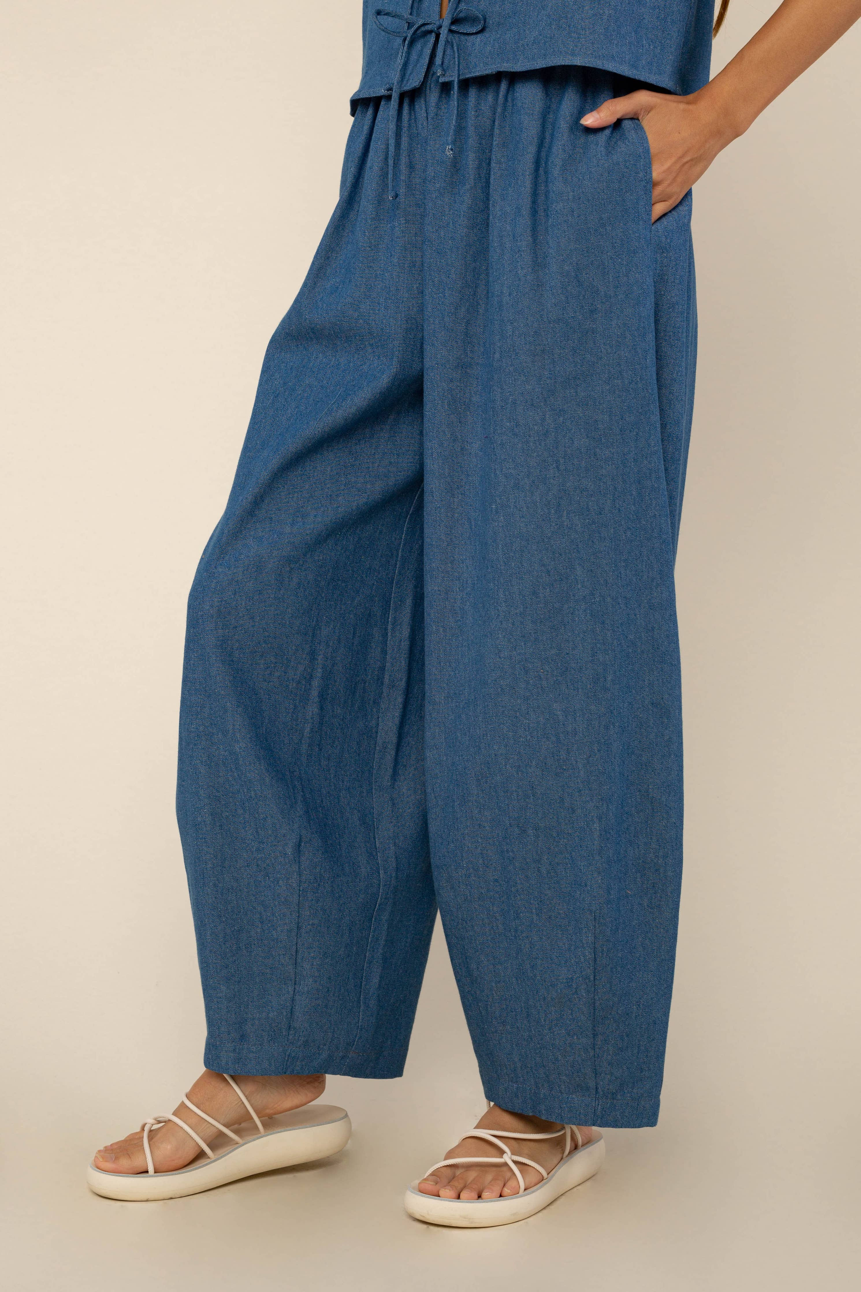 Woman facing away from the camera wearing denim, high rise, barrel jeans with a medium wash color and matching top 