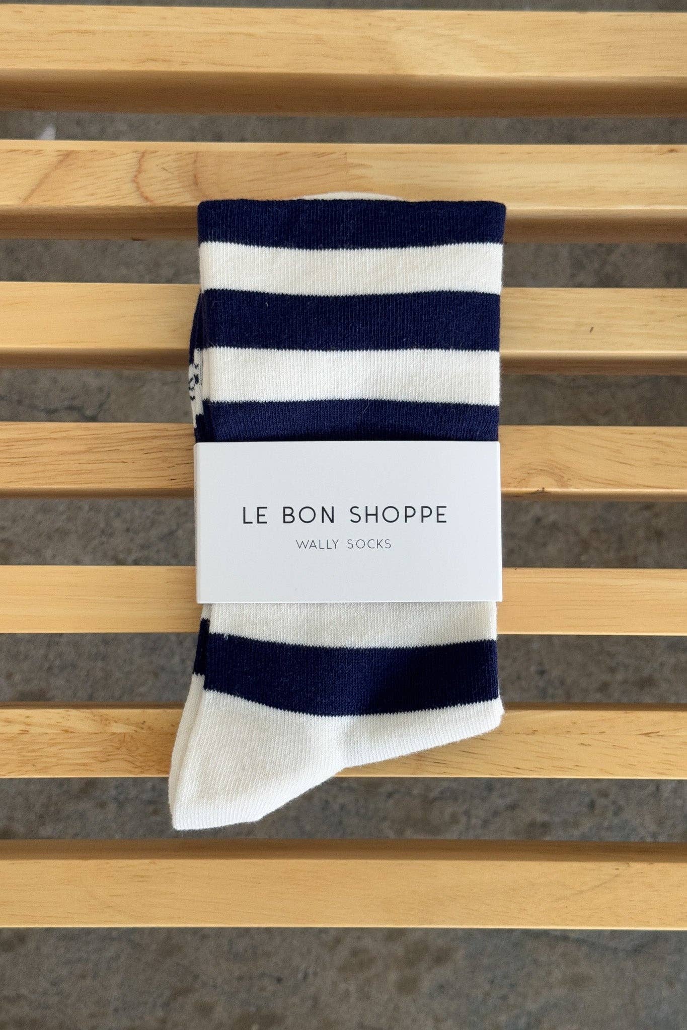Pair of striped socks with 'Le Bon Shoppe' label on a wooden surface
