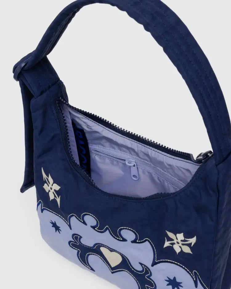 Inside view of Navy blue handbag with decorative western elements on a light gray background