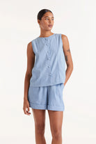 Woman wearing  blue denim like sleeveless  button down top and matching shorts