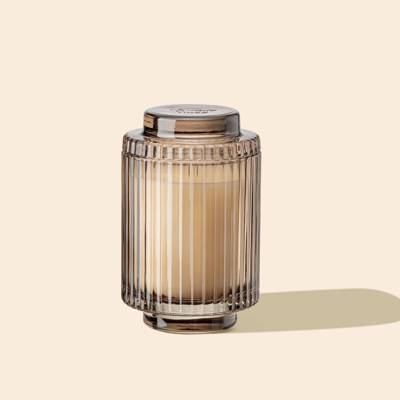 Decorative glass jar with a candle inside on a beige background