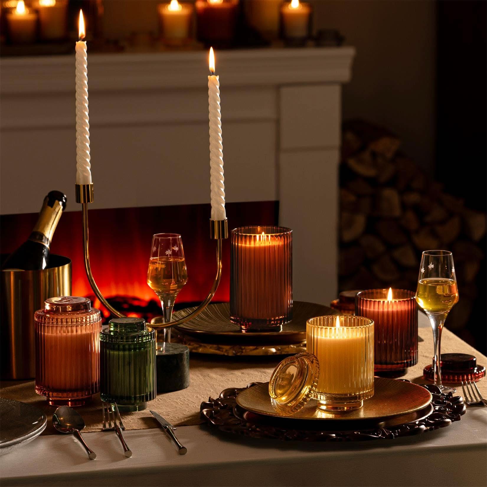 Candlelit table setting with wine glasses and candles in a cozy room.