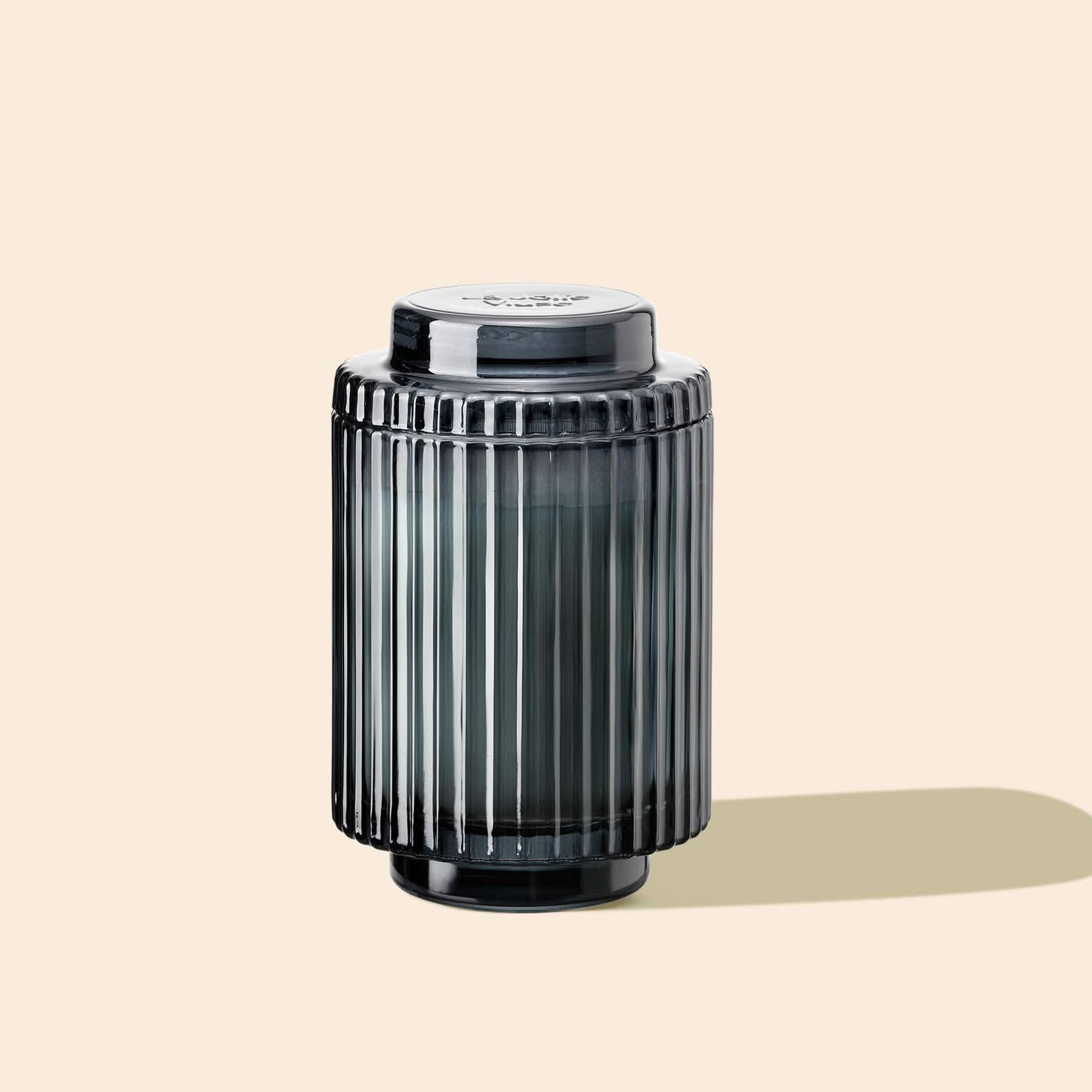 Dark gray cylindrical container with ribbed texture on a beige background