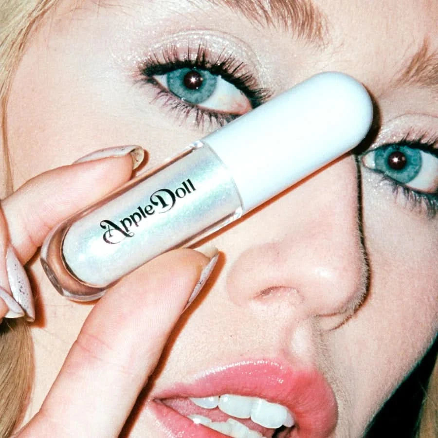 Close-up of a model holding the AppleDoll Cosmic Aphrodite Crème Shadow tube over her face