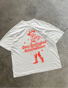 White oversized tee-shirt that has Star Spangled Smokeshow in bright red letters with a bright red cowgirl on the front. 