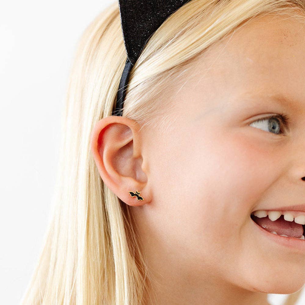 Close-up of a girl wearing a black bow headband and small earrings.