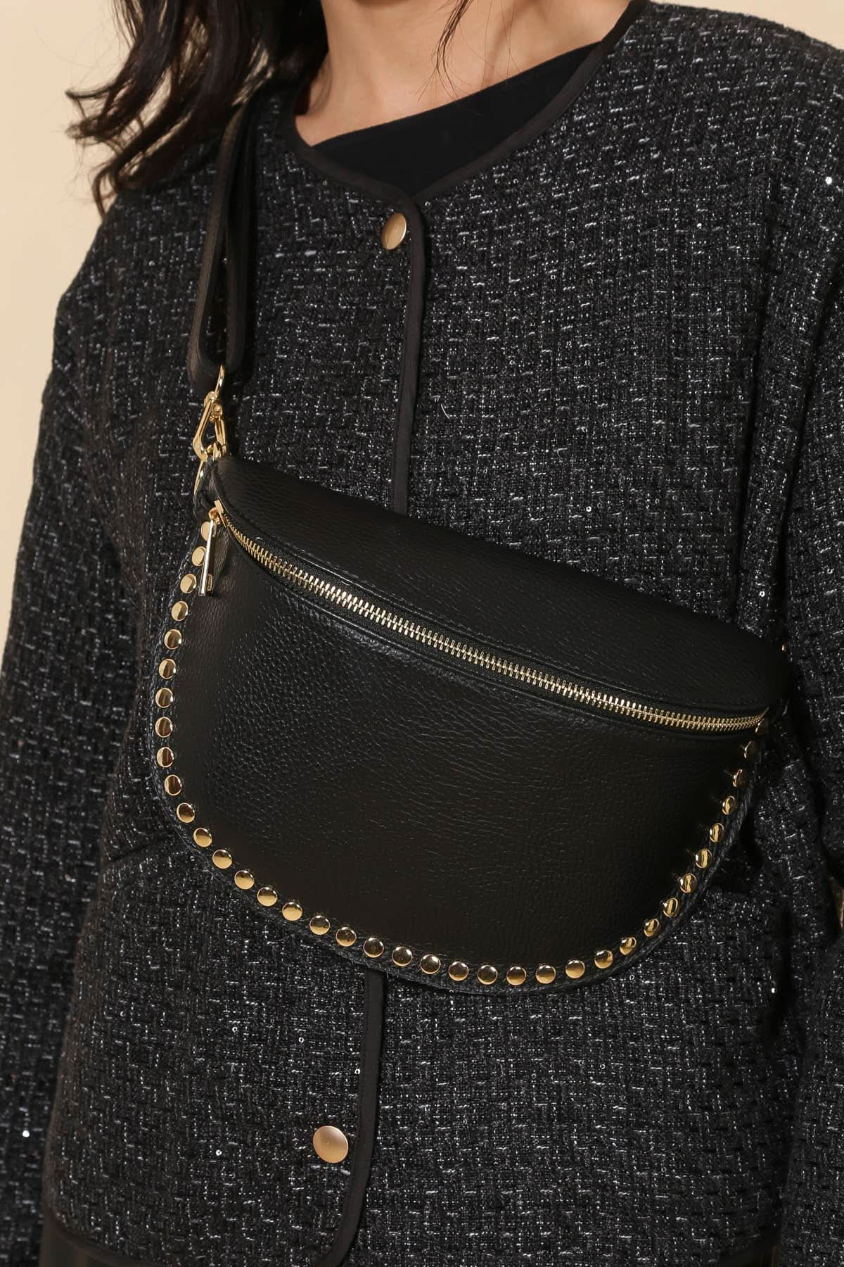 Black waist bag with gold studs worn by a person in a textured black outfit.