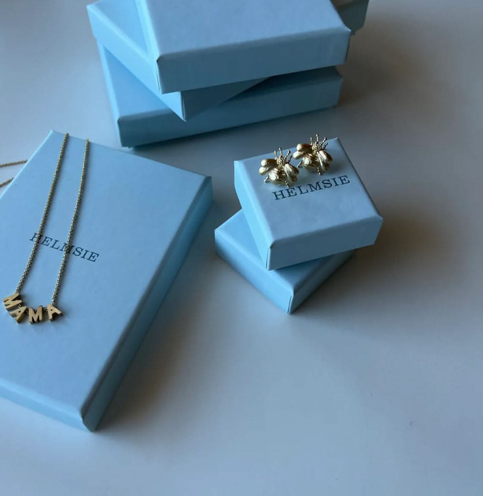 Jewelry set including a necklace and earrings on HELMSIE branded boxes.