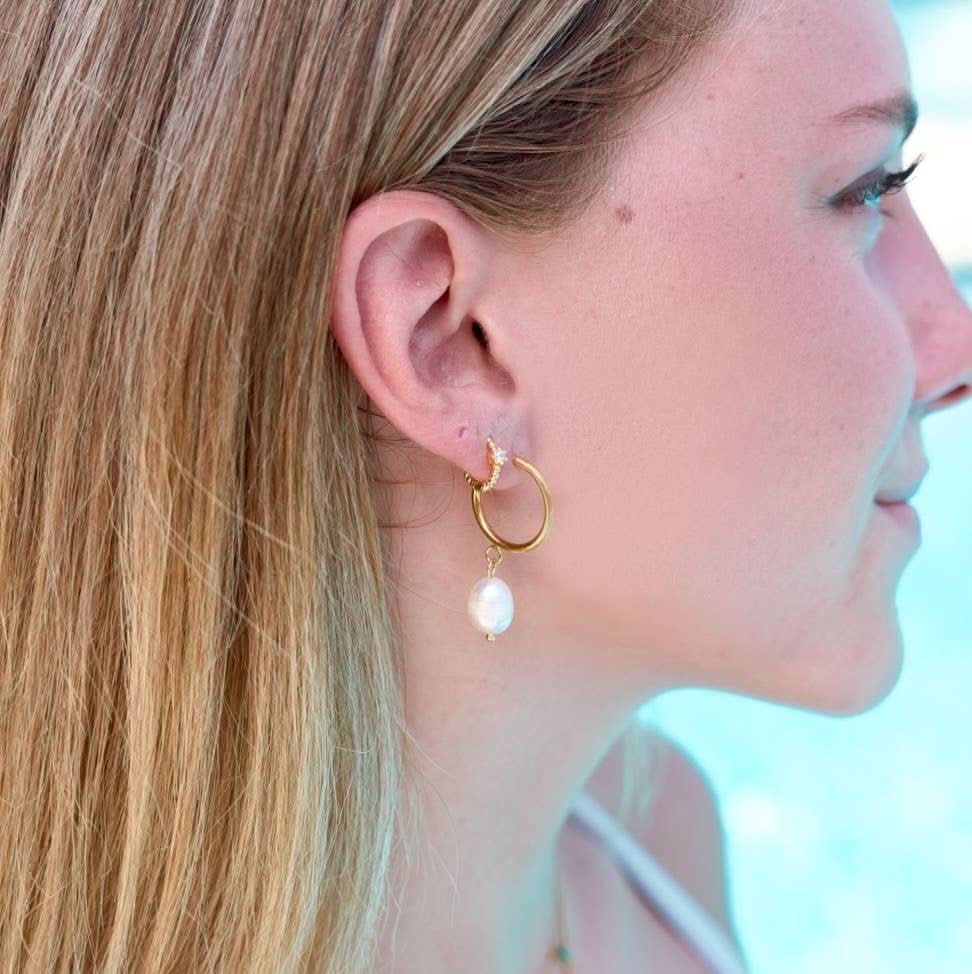 Woman wearing Waterproof gold huggie earrings with single Crystal gem in second piercing  