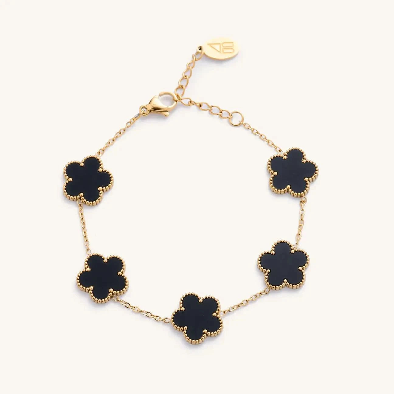 Gold bracelet with black clover-shaped charms on a white background