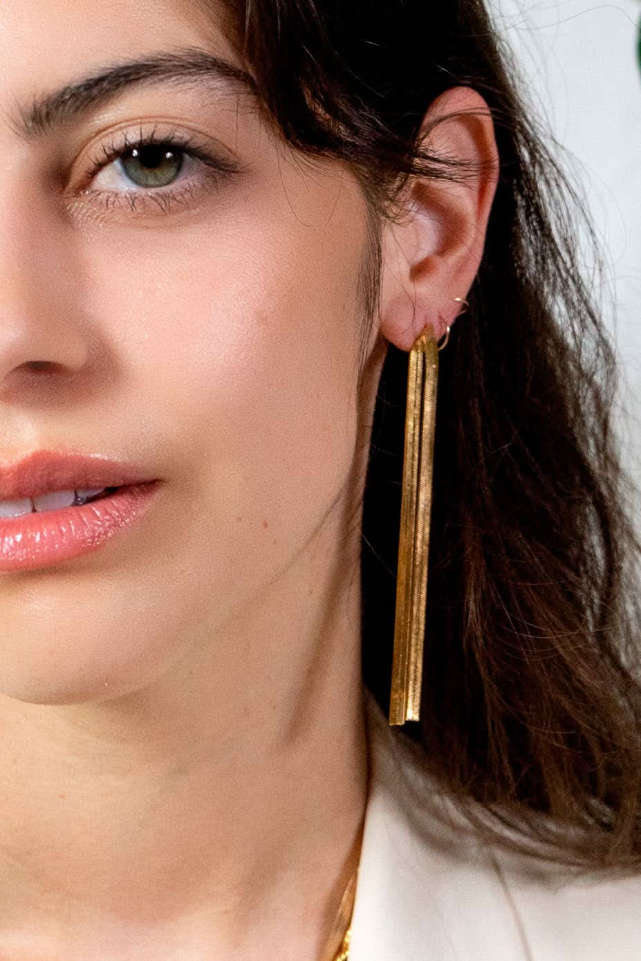 Close-up of a woman wearing gold earrings with a blurred background