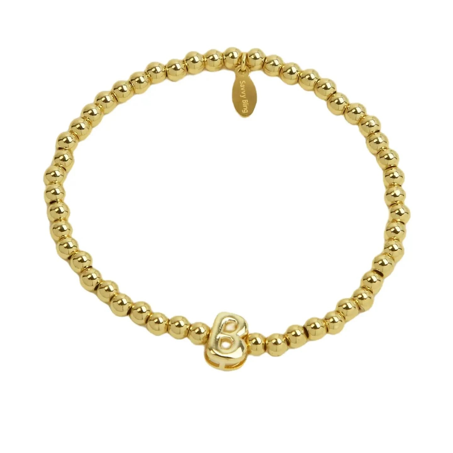 Gold beaded bracelet with a heart charm on a white background