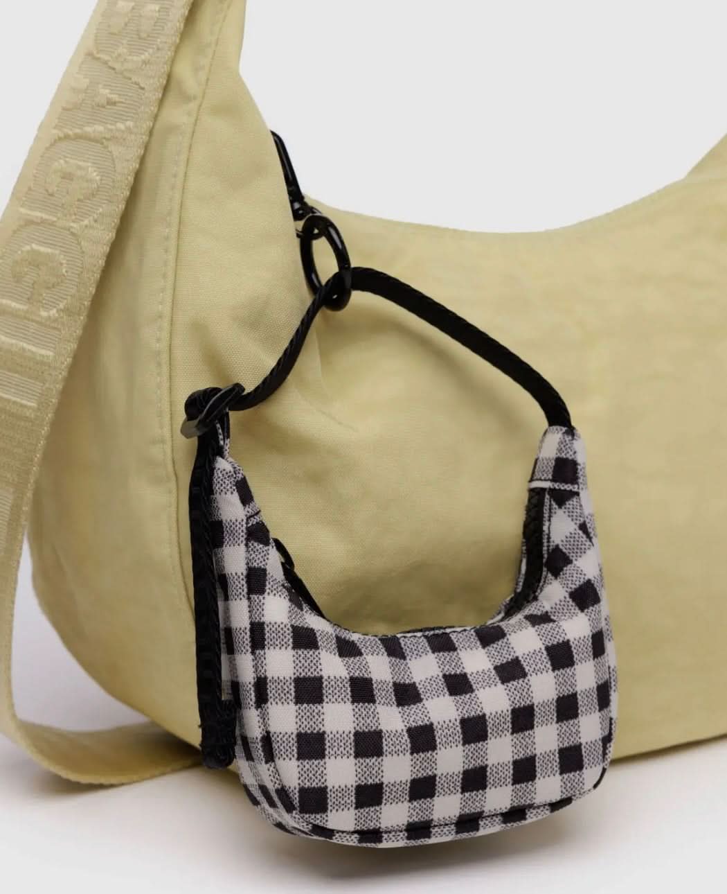 Black and white gingham mini BAGGU bag charm clipped onto yellow normal sized BAGGU crescent bag 