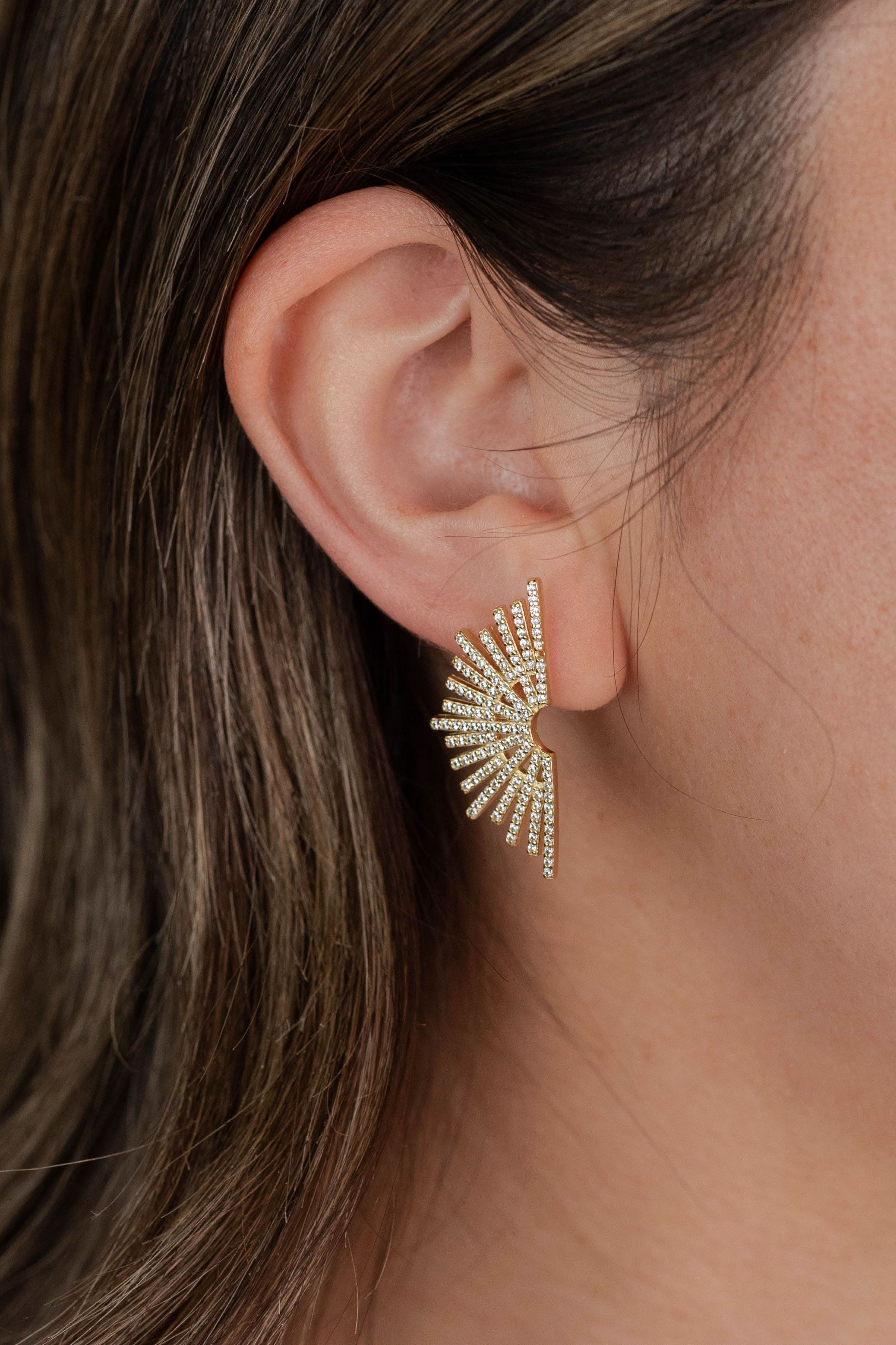 Close-up of an ear wearing a sparkling earring with a neutral background