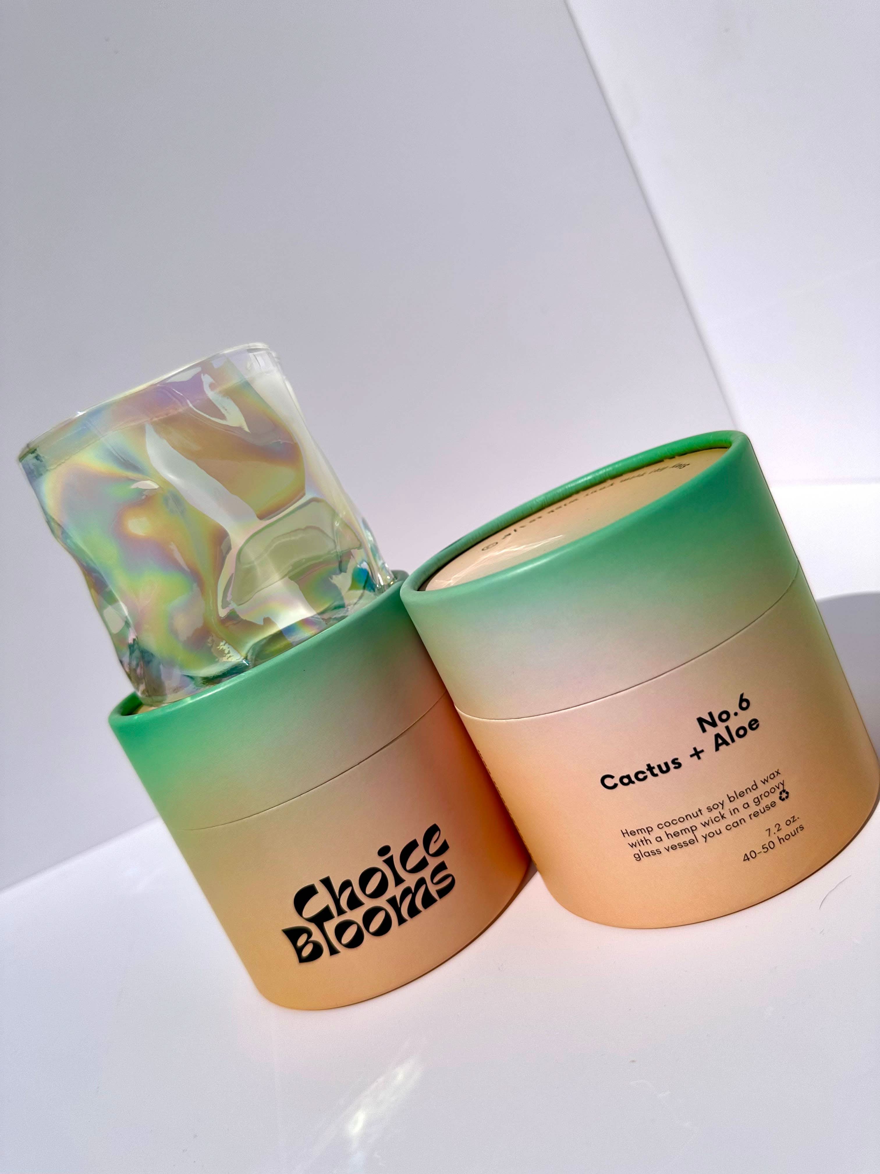 1 candle in a wavy glass with 2 green and orange candle packaging 