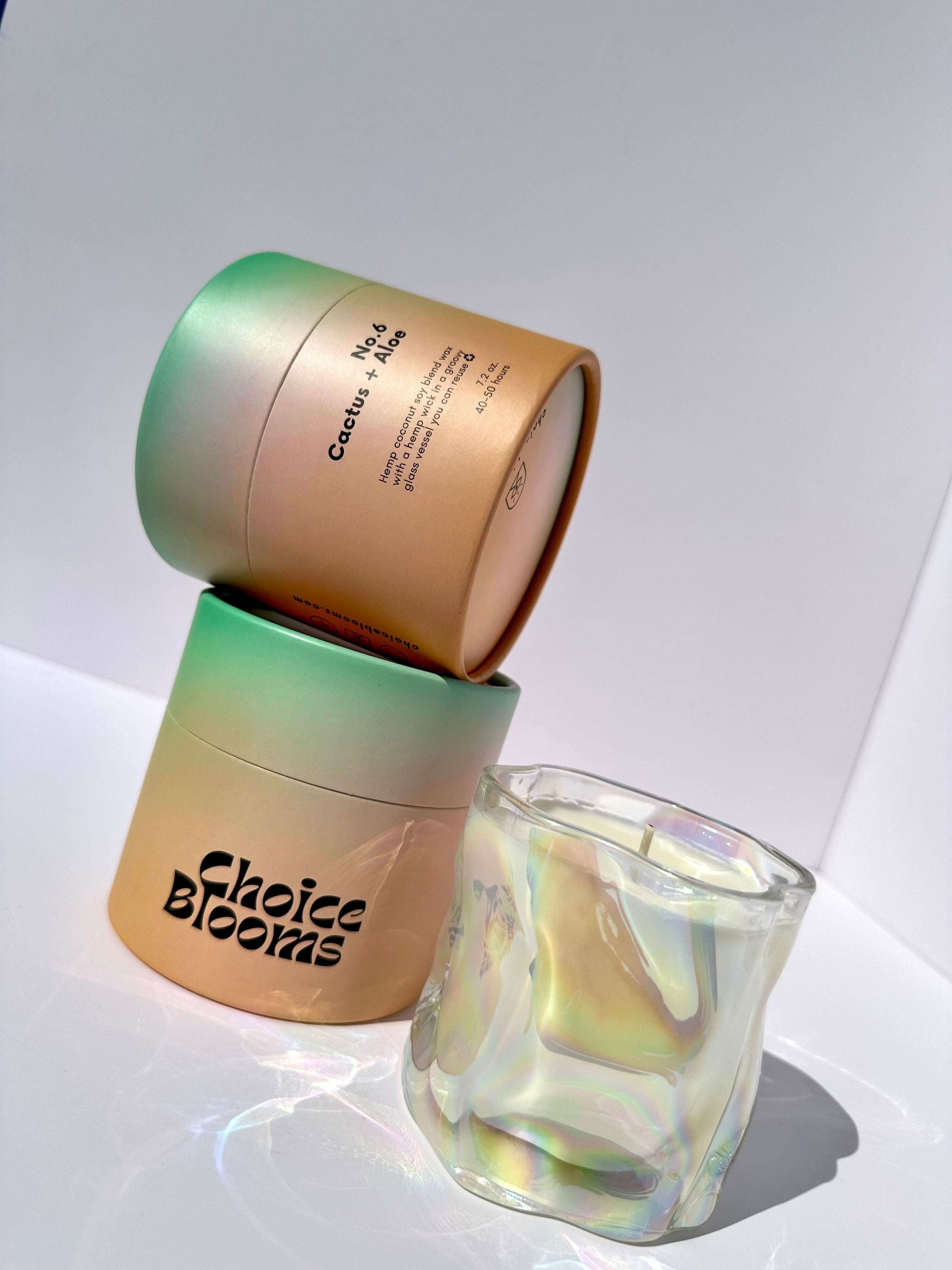 1 candle in a wavy glass with 2 green and orange candle packaging 