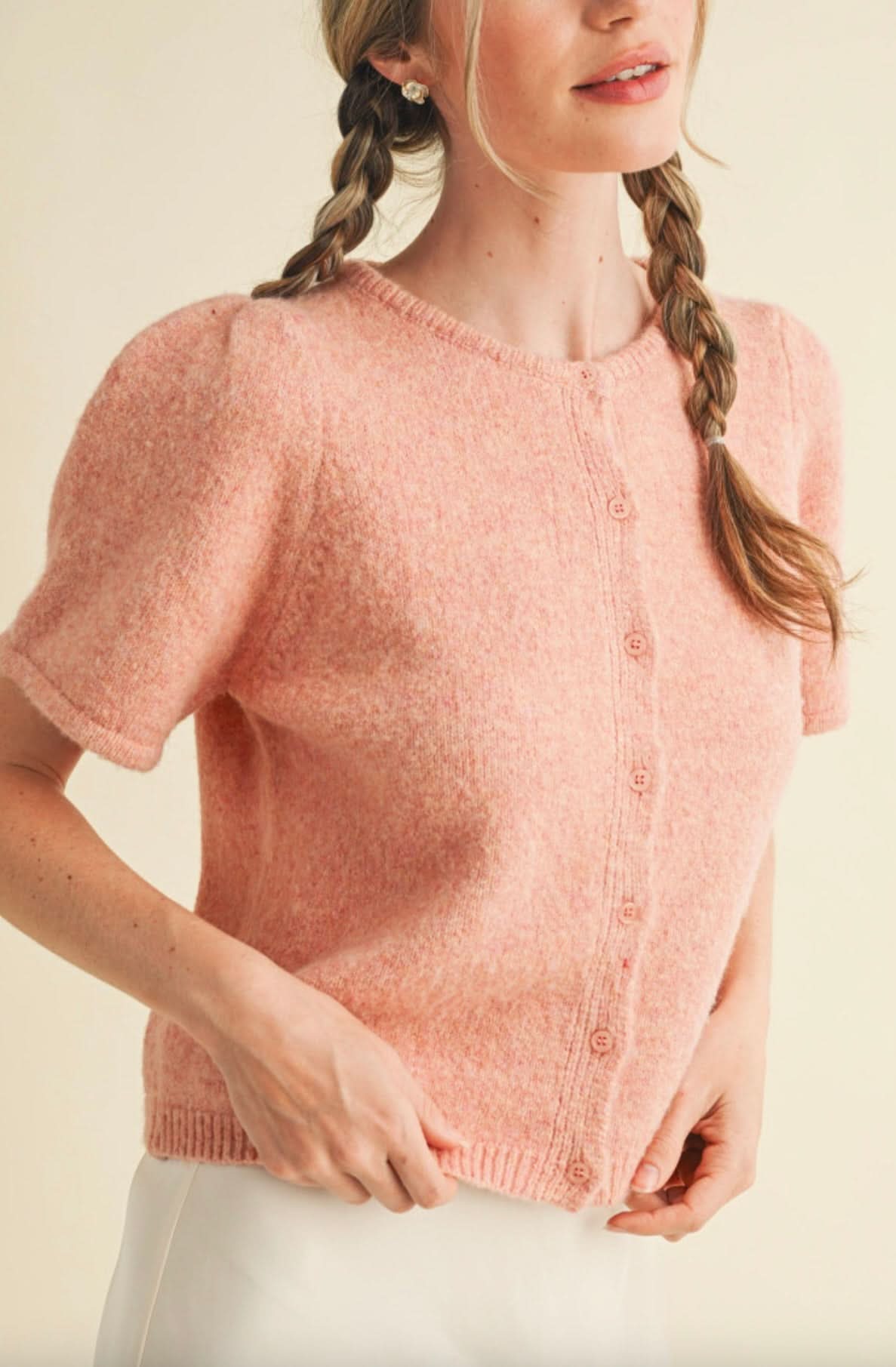 Woman wearing peach pink, fuzzy, short sleeved, button up cardigan