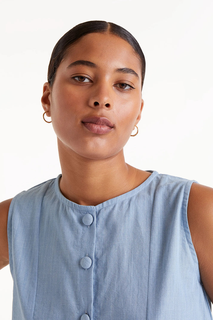 Woman wearing  blue denim like sleeveless  button down top 