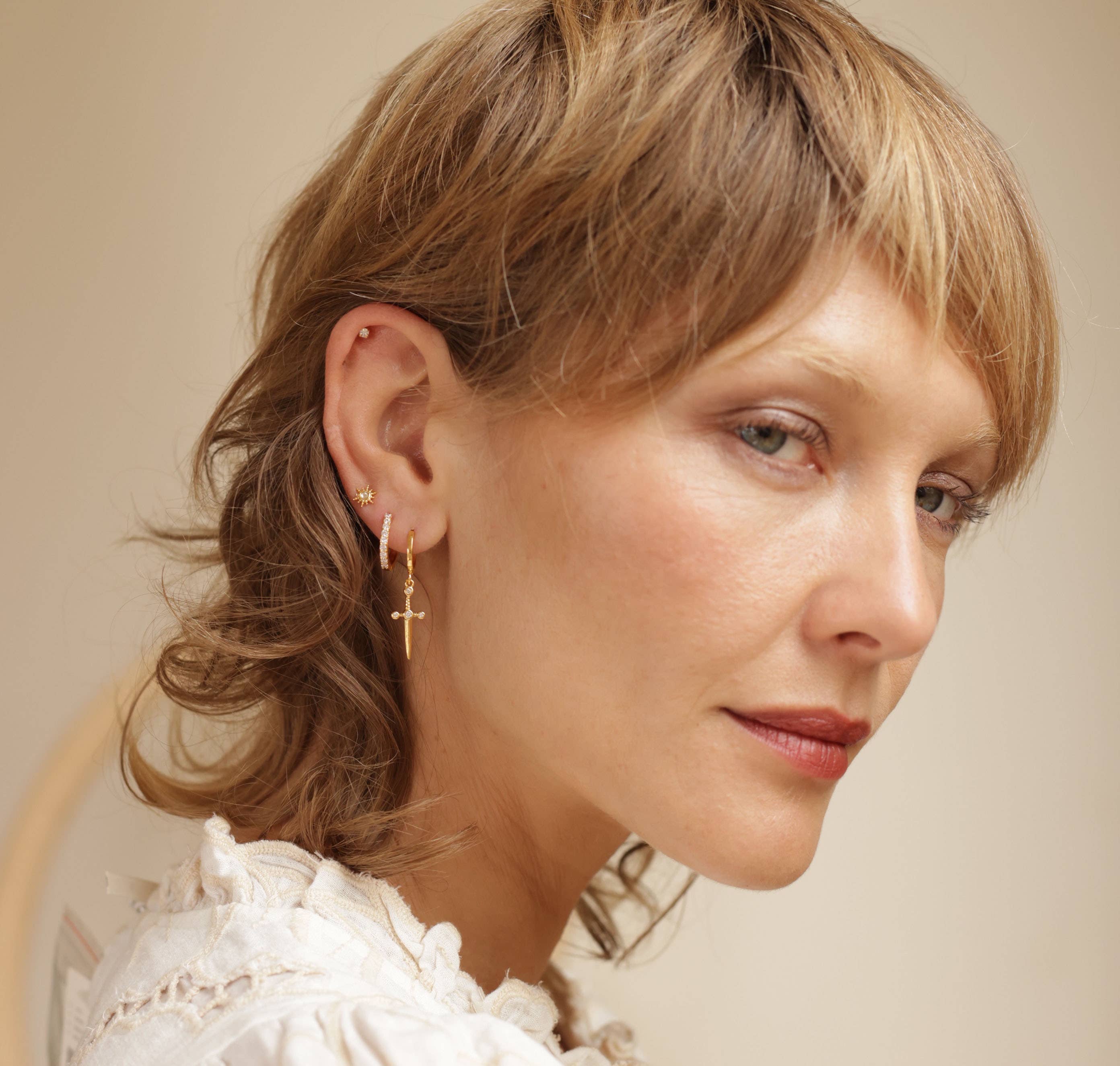 Close-up of a woman wearing gold earrings with a neutral glow