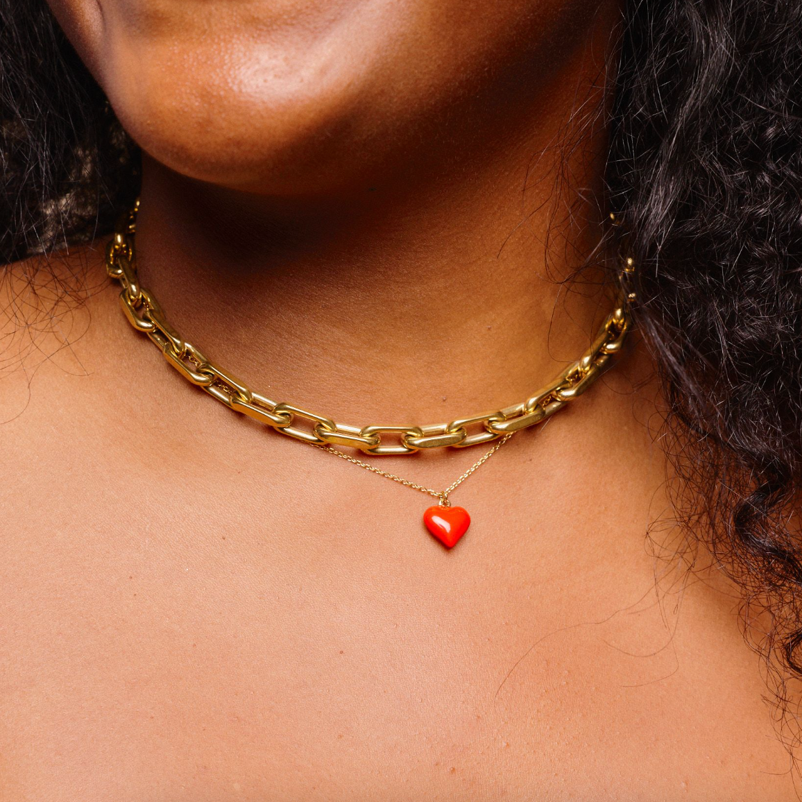 Woman wearing a necklace stack including a gold, waterproof, chunky link choker