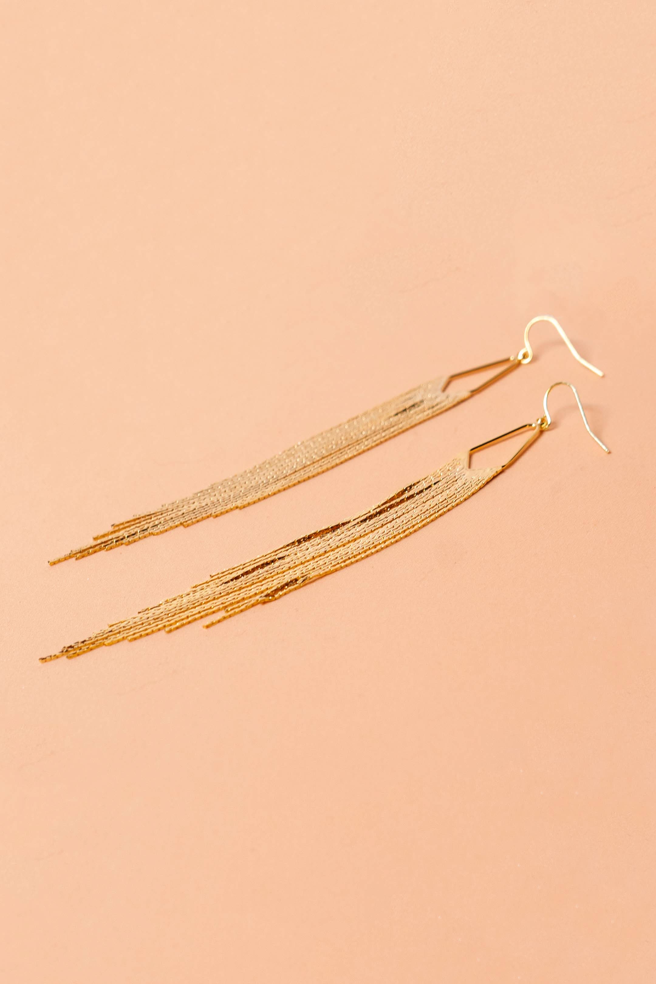 Gold earrings on a beige background
