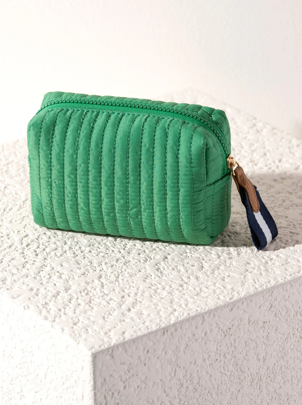 Green textured pouch with a zipper on a textured white surface