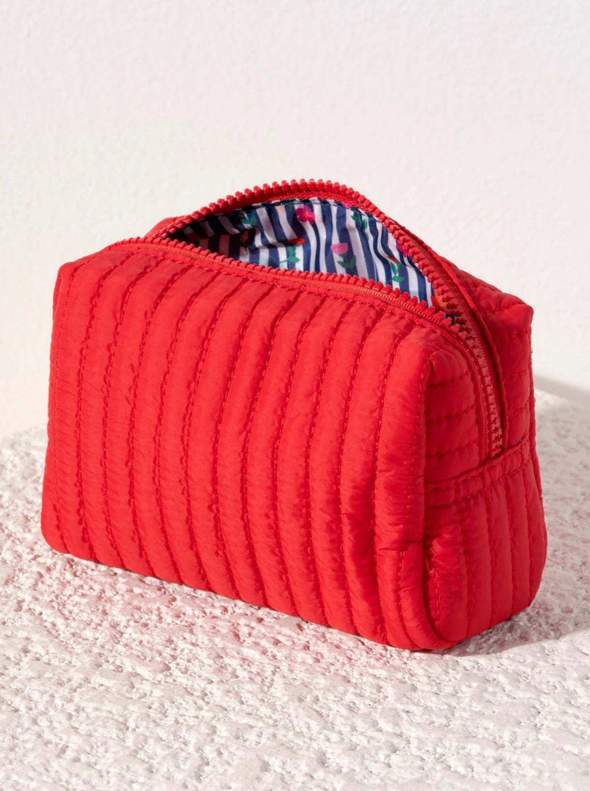Ezra small boxy cosmetic pouch Red quilted pouch on a textured white surface